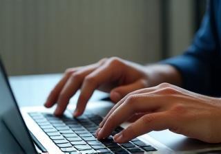Person typing a report on a laptop
